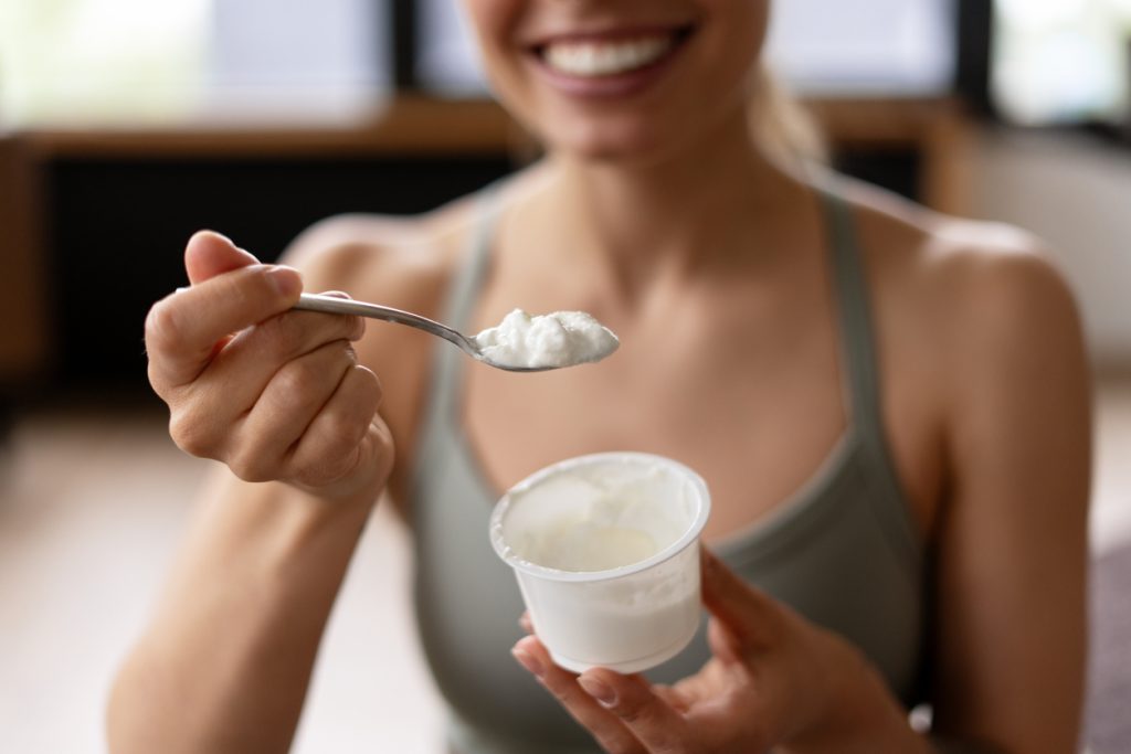 Mulher jovem consumindo iogurte natural como fonte de proteína