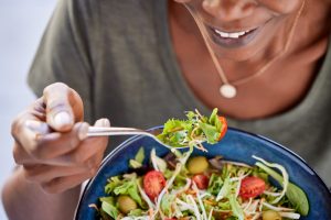 Mulher se alimentando de forma saudável com prato de salada