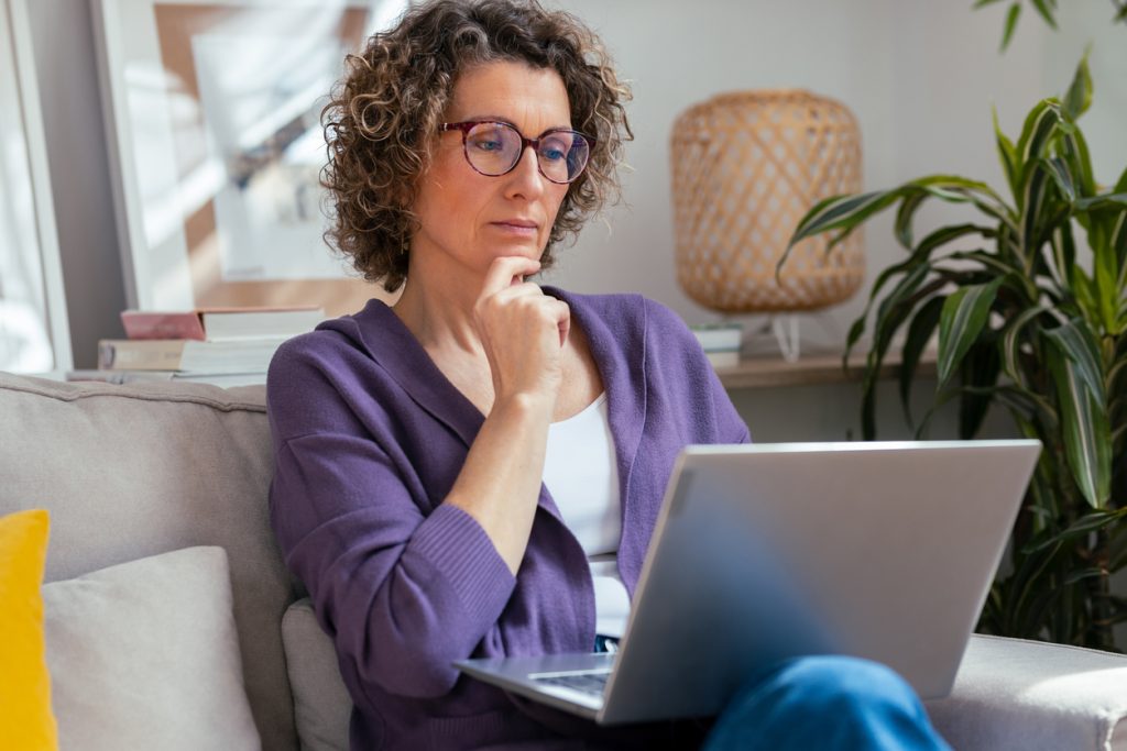 Mulher sentada no sofá pesquisando no notebook sobre uso de canetas emagrecedoras