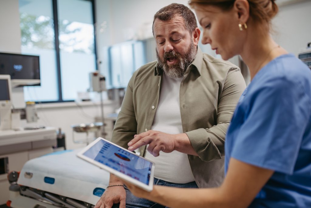Médica explica os sintomas e resultados de exames de gordura no fígado para paciente em um consultório clínico.