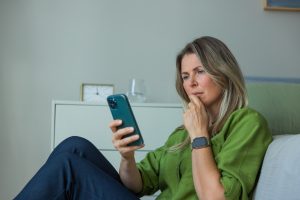 Mulher sentada no chão, pesquisando no celular sobre uso de canetas emagrecedoras