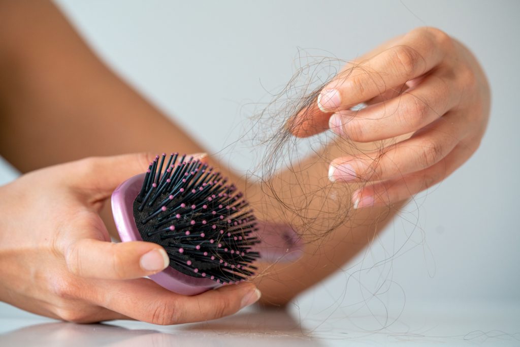 Mulher indicando queda de cabelo ao limpar sua escova