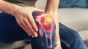 Uma pessoa segurando o joelho dolorido, com uma sobreposição de raios-X que mostra inflamação na articulação do joelho, ilustrando onde podemos ter dor articular. A perda de peso ajuda a aliviar esse tipo de inflamação.