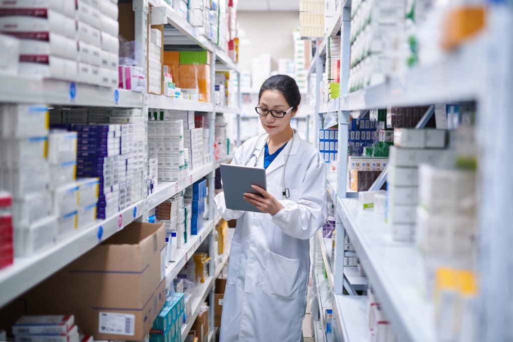 Farmacêutica de jaleco consultando um tablet entre prateleiras de medicamentos, ilustrando a disponibilidade da SEMAVY para o tratamento do diabetes tipo 2