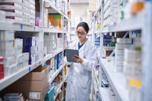 Farmacêutica de jaleco consultando um tablet entre prateleiras de medicamentos, ilustrando a disponibilidade da SEMAVY para o tratamento do diabetes tipo 2