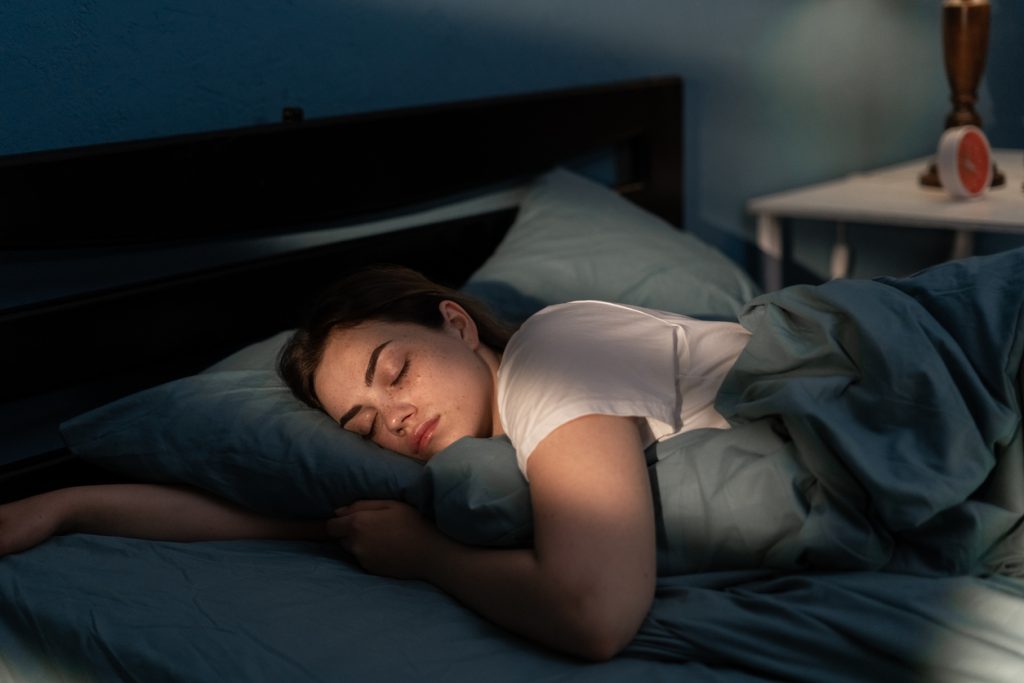 Mulher dormindo tranquilamente na cama durante a noite, ilustrando a importância do sono para baixar os níveis de cortisol